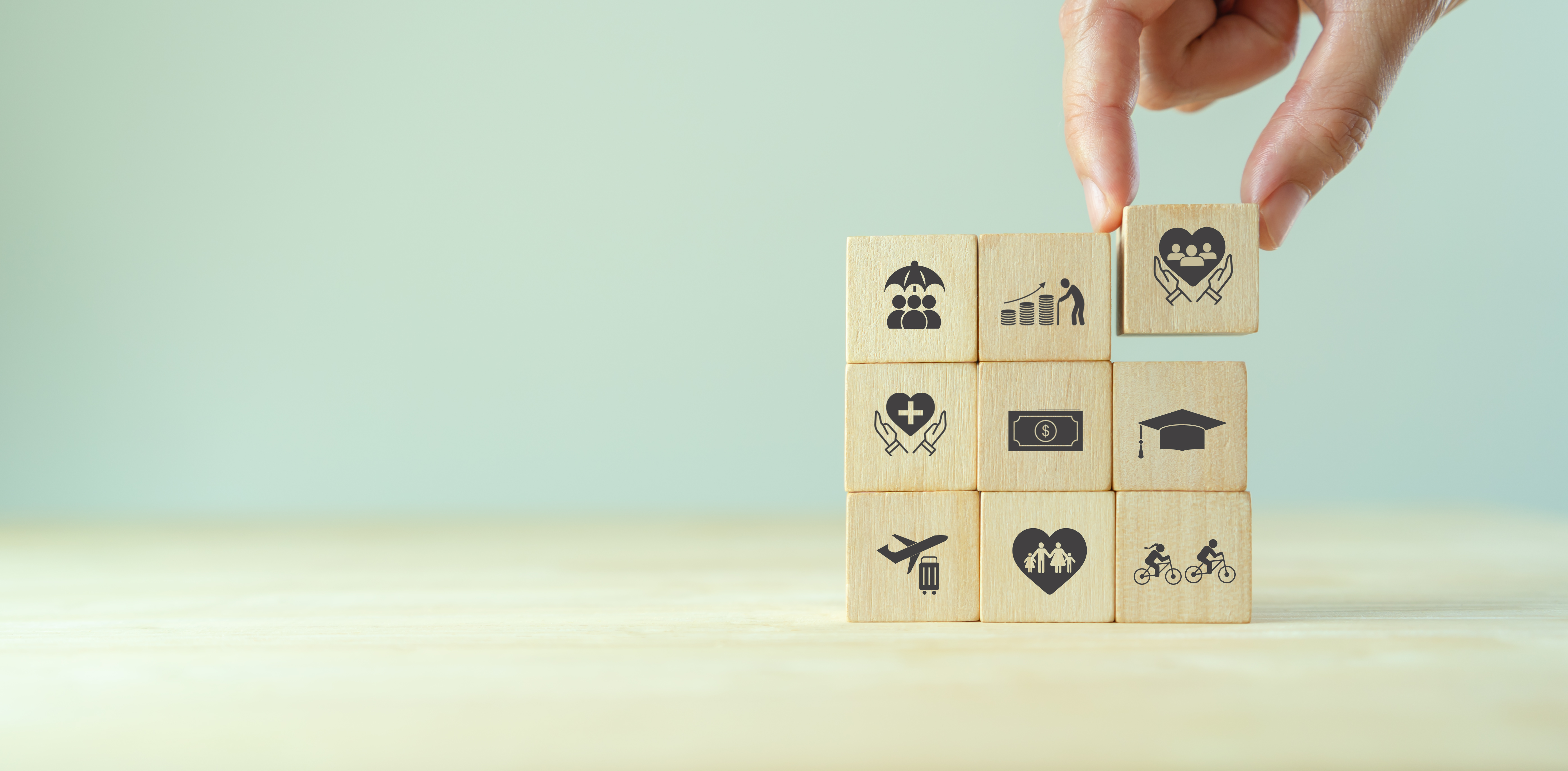 torre 3 per 3 di cubetti di legno che rappresentano gli elementi chiave di un piano welfare: viaggi, salute, educazione e istruzione, tempo libero, famiglia, ...